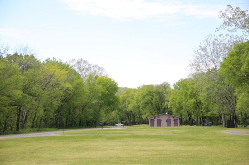 A large grassy field with a restroom at the end.