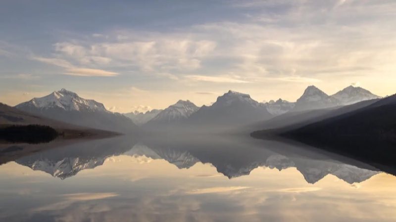Lake McDonald with mountains in the background and pebble shore in the foreground.