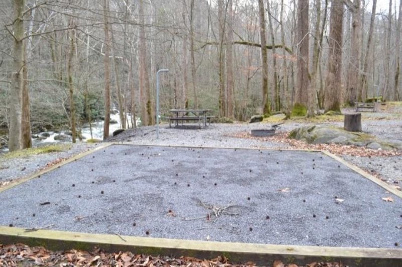 A wooded campsite with gravel tent pad