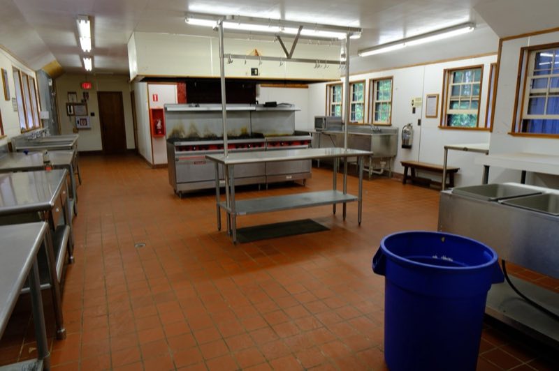 Commercial Kitchen with waste baskets, stainless steel counters, sinks, and gas stoves and griddles