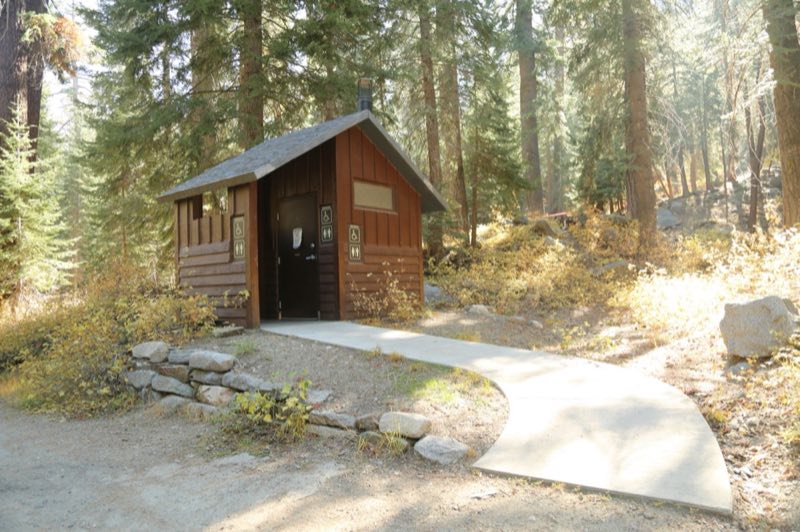 A sloping concrete path leads to a primitive toilet