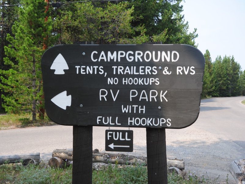 Brown wooden park service sign with campground information and RV park information