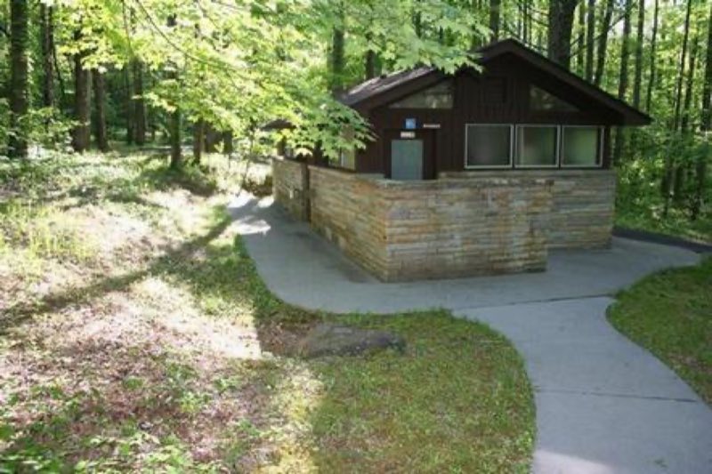 Paved walkway leads to a wooden restroom structure