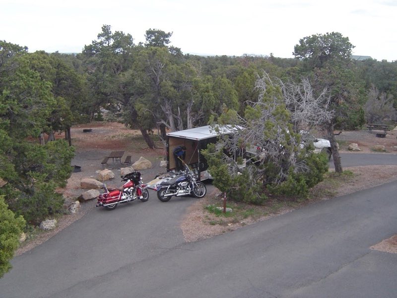 Two motorcycles behind a trailer in a campsite