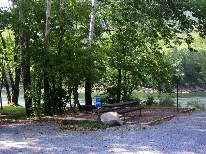 A campsite next to the river with a sign that designates it as an accessibility only campsite.