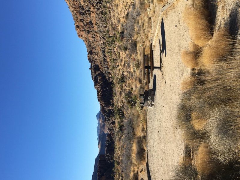 A campsite: cleared area, raised fire pit, picnic table, rock formations, desert shrubbery