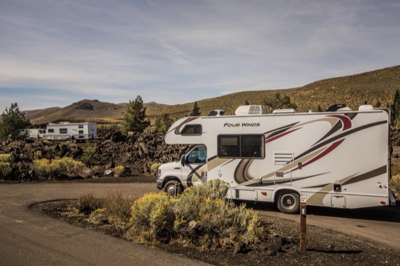 an RV parked in a pull through campsite among sagebrush, a second RV is at the neighboring site