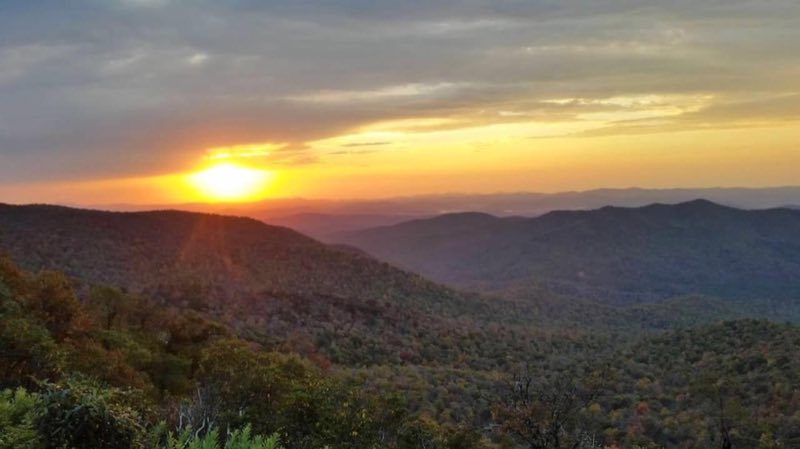 Yellow and red sky as the sun sinks below mountains on the horizon