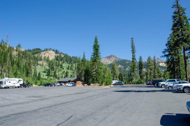 A parking area with vehicles parked on the edges and a building at the far end.
