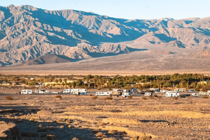 a long distance view of RVs and trailers in a gravel area with distant mountains