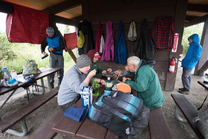 people sitting at a picnic table in a sheltered area